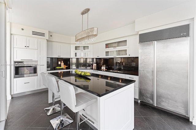 kitchen with white cabinets, paneled built in refrigerator, a breakfast bar, and oven