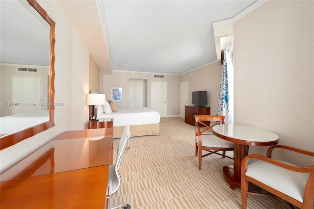 bedroom with ornamental molding and light carpet