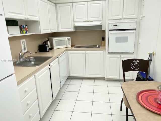 kitchen with sink, white appliances, light tile patterned flooring, and white cabinetry