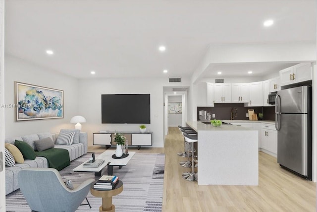 living room featuring sink and light hardwood / wood-style flooring