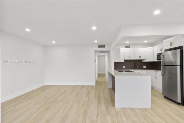 kitchen with white cabinetry, appliances with stainless steel finishes, light wood-type flooring, a kitchen island, and tasteful backsplash