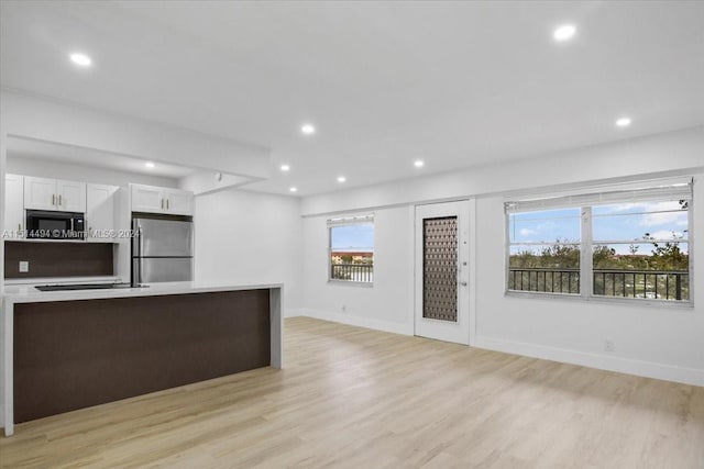 kitchen with white cabinetry, light hardwood / wood-style floors, stainless steel refrigerator, and a kitchen island