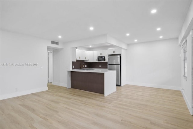 kitchen with white cabinets, light hardwood / wood-style flooring, and stainless steel refrigerator