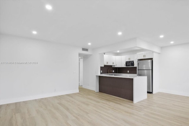 kitchen featuring backsplash, stainless steel fridge, sink, light hardwood / wood-style flooring, and white cabinets