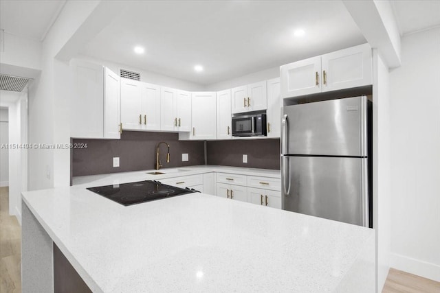 kitchen featuring sink, backsplash, black appliances, white cabinetry, and light wood-type flooring