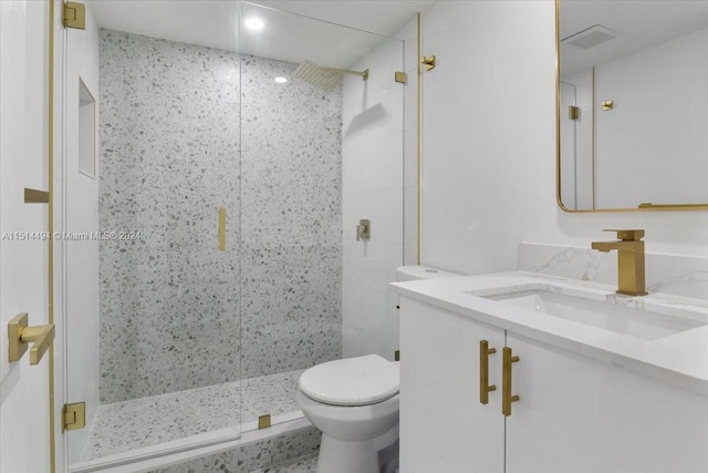 bathroom featuring toilet, vanity, and a shower with shower door