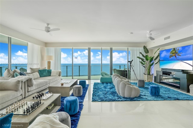 living room featuring light tile flooring, a water view, ceiling fan, and plenty of natural light