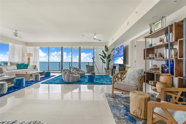 living area with plenty of natural light, a water view, ceiling fan, and light tile floors