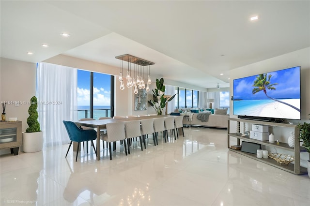 tiled dining area featuring a water view, plenty of natural light, and an inviting chandelier