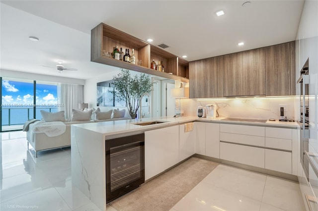 kitchen featuring light tile floors, tasteful backsplash, wine cooler, white cabinetry, and black electric stovetop