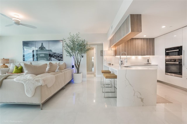 living room featuring ceiling fan, light tile floors, and sink