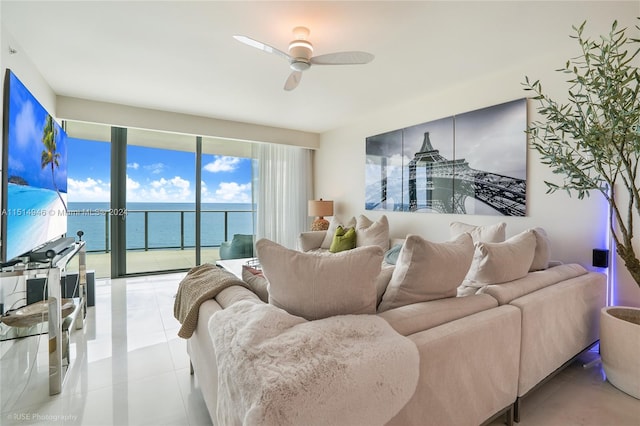 living room with a water view, ceiling fan, and light tile floors