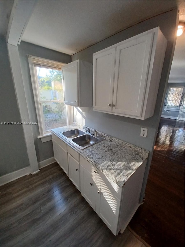 kitchen featuring light stone counters, sink, dark hardwood / wood-style flooring, and white cabinetry