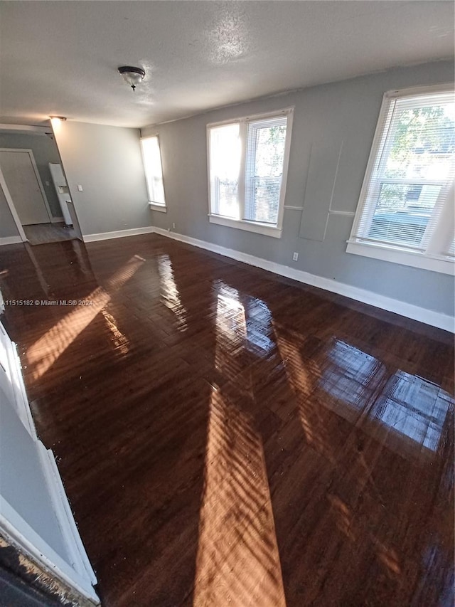 empty room featuring plenty of natural light, dark hardwood / wood-style floors, and a textured ceiling