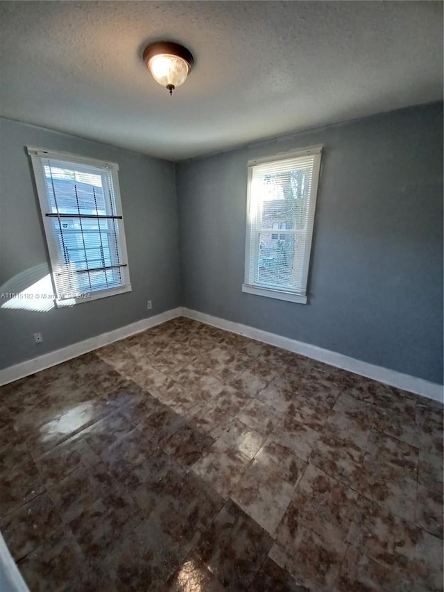 unfurnished room featuring a textured ceiling and tile floors