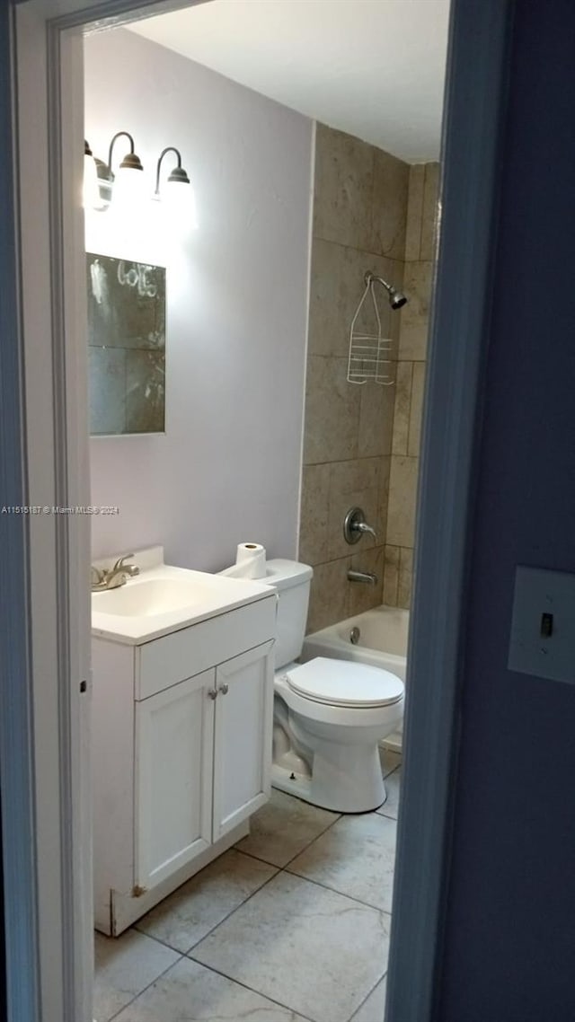 full bathroom featuring tiled shower / bath, toilet, tile floors, and vanity