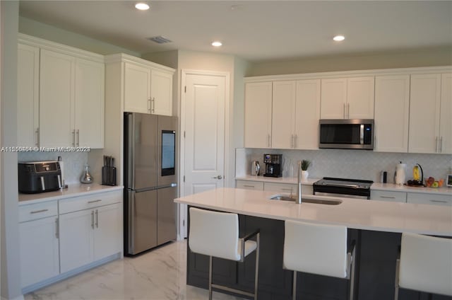 kitchen featuring white cabinets, appliances with stainless steel finishes, tasteful backsplash, and light tile flooring