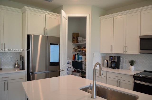 kitchen featuring white cabinets, appliances with stainless steel finishes, tasteful backsplash, and sink