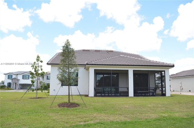 rear view of property featuring a lawn and a sunroom