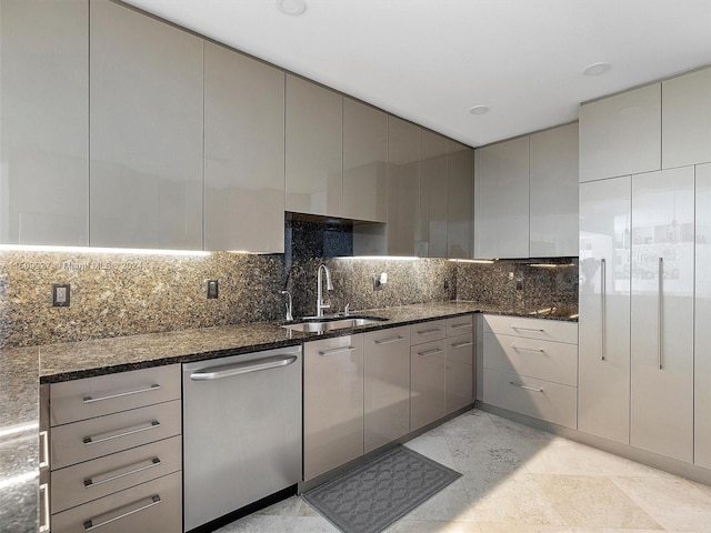 kitchen featuring dark stone counters, stainless steel dishwasher, backsplash, gray cabinets, and sink