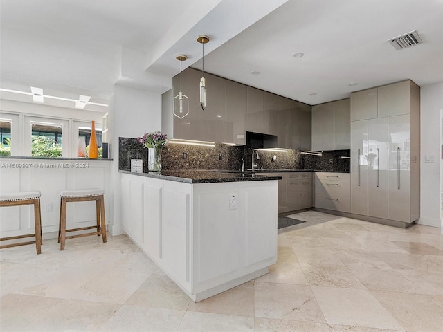 kitchen with gray cabinetry, pendant lighting, decorative backsplash, and kitchen peninsula