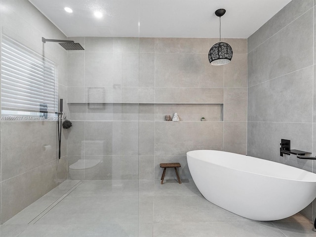 bathroom with tiled shower, tile patterned flooring, and tile walls