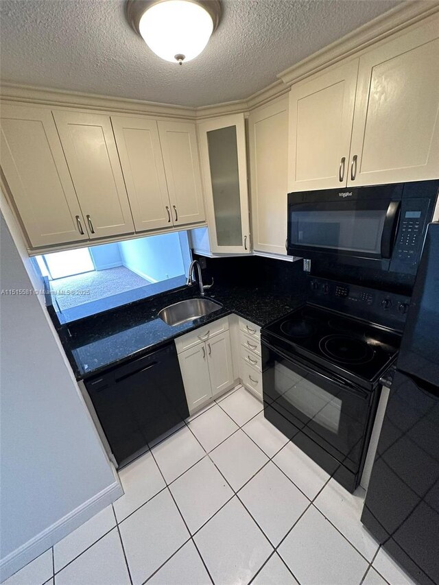 kitchen featuring light tile floors, a textured ceiling, black appliances, dark stone countertops, and sink