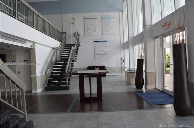 entrance foyer featuring elevator, light tile flooring, and a towering ceiling