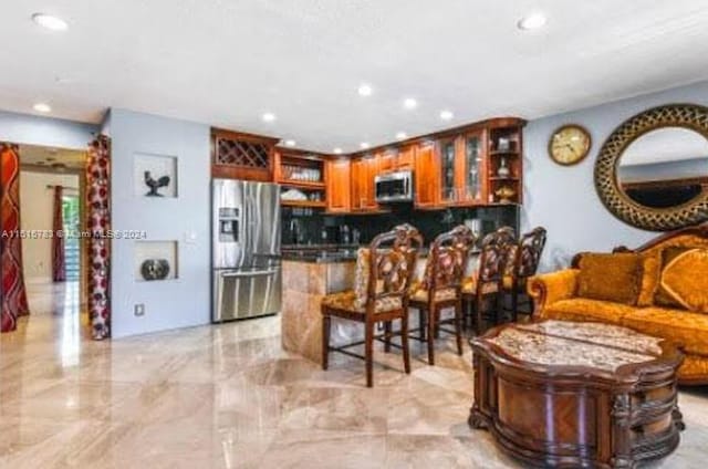 kitchen with light tile floors, backsplash, a breakfast bar area, and stainless steel appliances