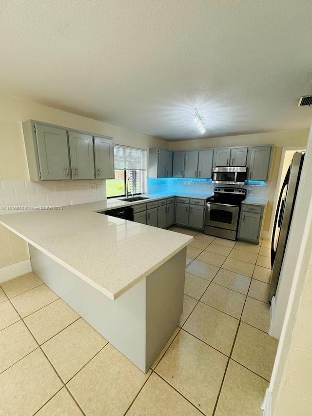 kitchen with kitchen peninsula, light tile flooring, appliances with stainless steel finishes, and sink