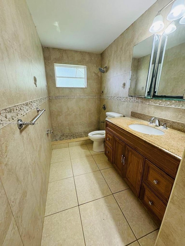 bathroom featuring tile flooring, large vanity, toilet, and tile walls