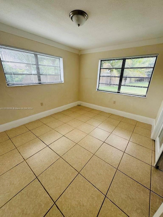 tiled empty room featuring ornamental molding