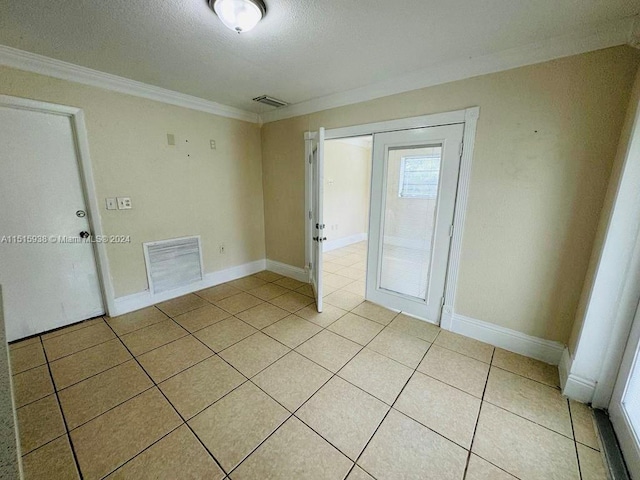 tiled empty room featuring crown molding and a textured ceiling