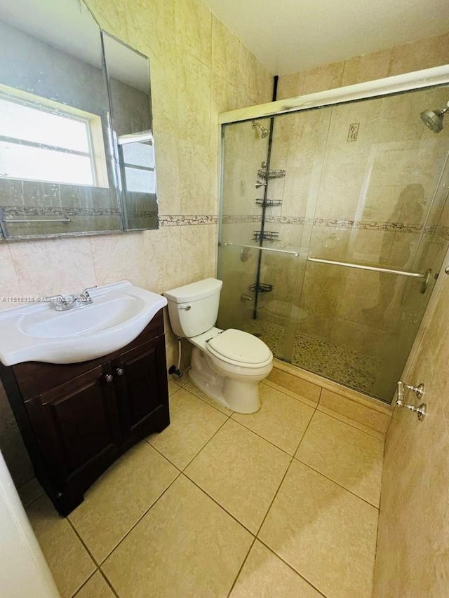 bathroom featuring vanity, tile walls, tile floors, a shower with door, and toilet