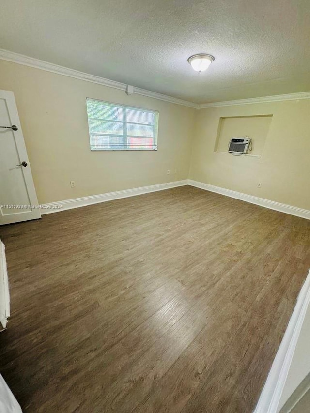 empty room with an AC wall unit, dark wood-type flooring, a textured ceiling, and crown molding