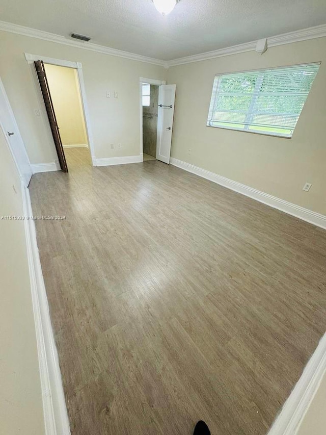 interior space featuring a textured ceiling, crown molding, and light hardwood / wood-style flooring