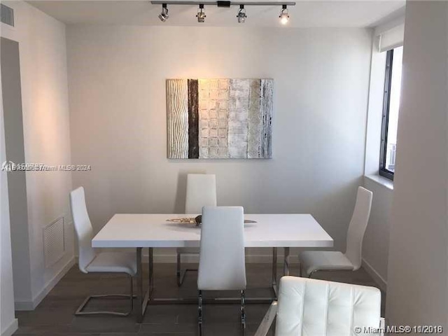 dining area with rail lighting and dark hardwood / wood-style floors