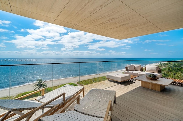 balcony featuring an outdoor living space, a water view, and a beach view