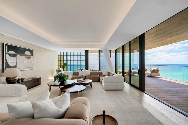 living room with a water view, a wall of windows, and light hardwood / wood-style floors