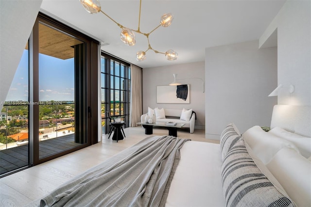 bedroom featuring access to exterior, light wood-type flooring, a chandelier, and floor to ceiling windows