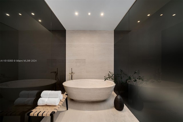 bathroom with a washtub and tile walls