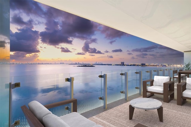 balcony at dusk featuring a water view