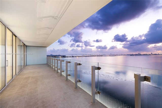 balcony at dusk featuring a water view