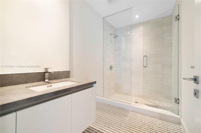 bathroom with tile flooring, a shower with shower door, and vanity