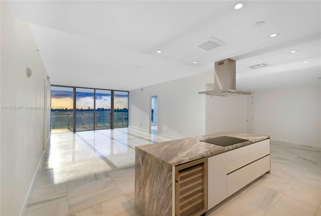 kitchen with island range hood, expansive windows, beverage cooler, black electric stovetop, and white cabinets