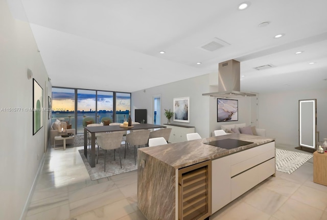 kitchen with light tile floors, island exhaust hood, black electric cooktop, beverage cooler, and a center island