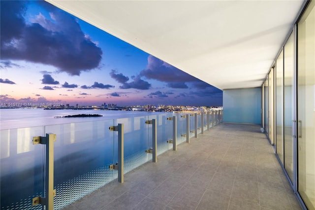 balcony at dusk featuring a water view