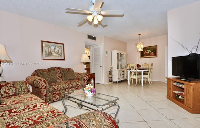 tiled living room with a textured ceiling and ceiling fan with notable chandelier