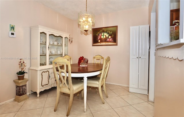 tiled dining area with a chandelier and a textured ceiling