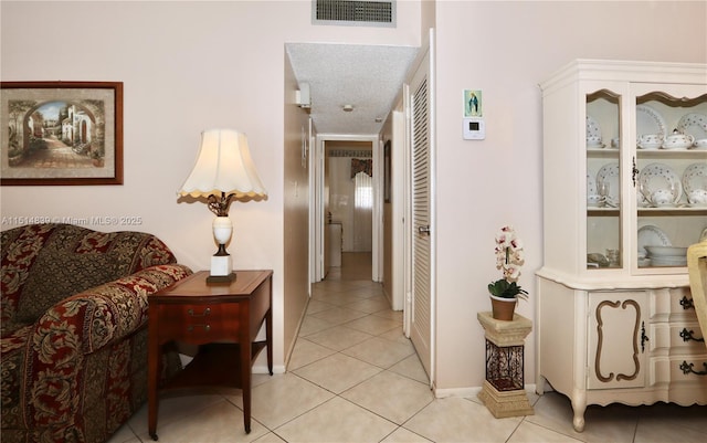 corridor with a textured ceiling and light tile patterned flooring